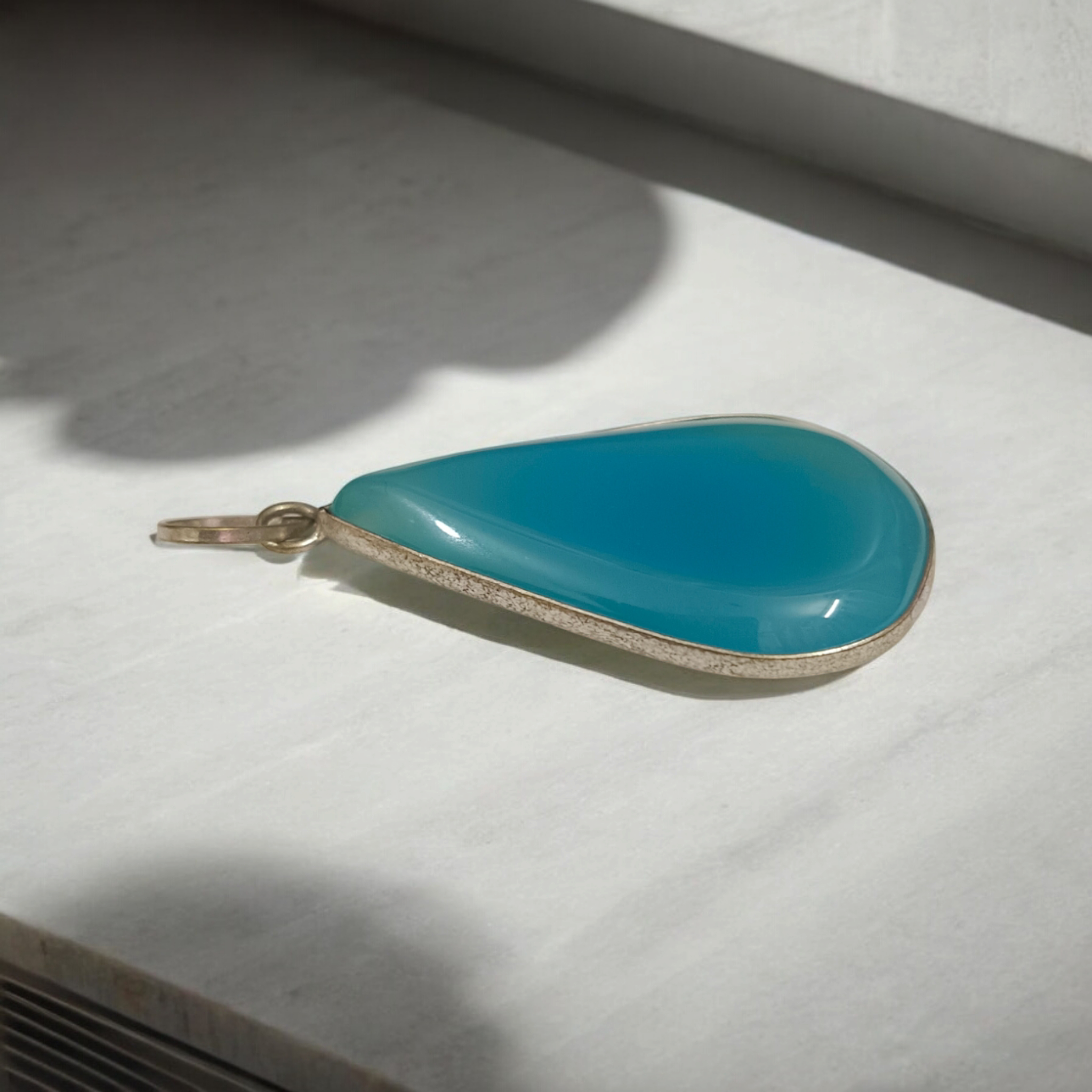 Original Firoza pendant with a vibrant turquoise hue, displayed on a necklace, highlighting its polished finish and elegant design.