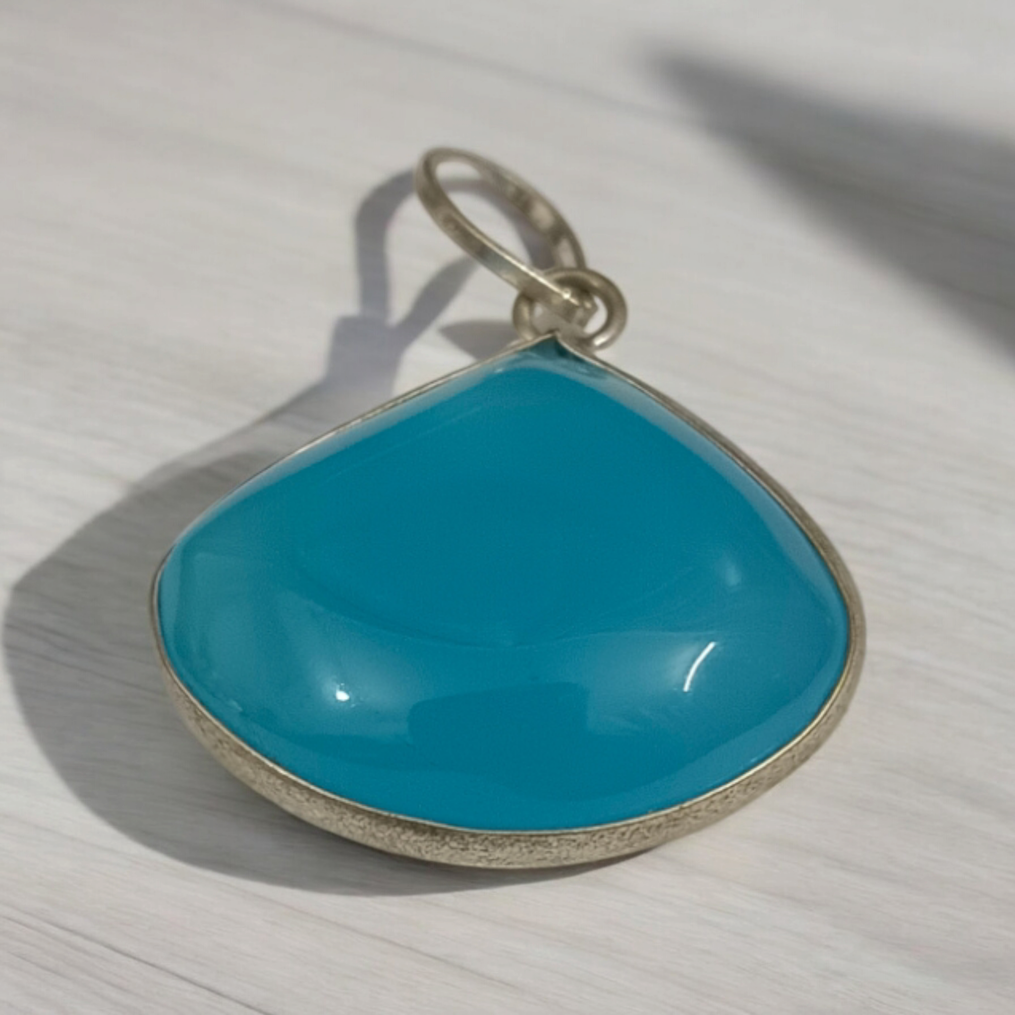 Original Firoza pendant with a vibrant turquoise hue, displayed on a necklace, highlighting its polished finish and elegant design.