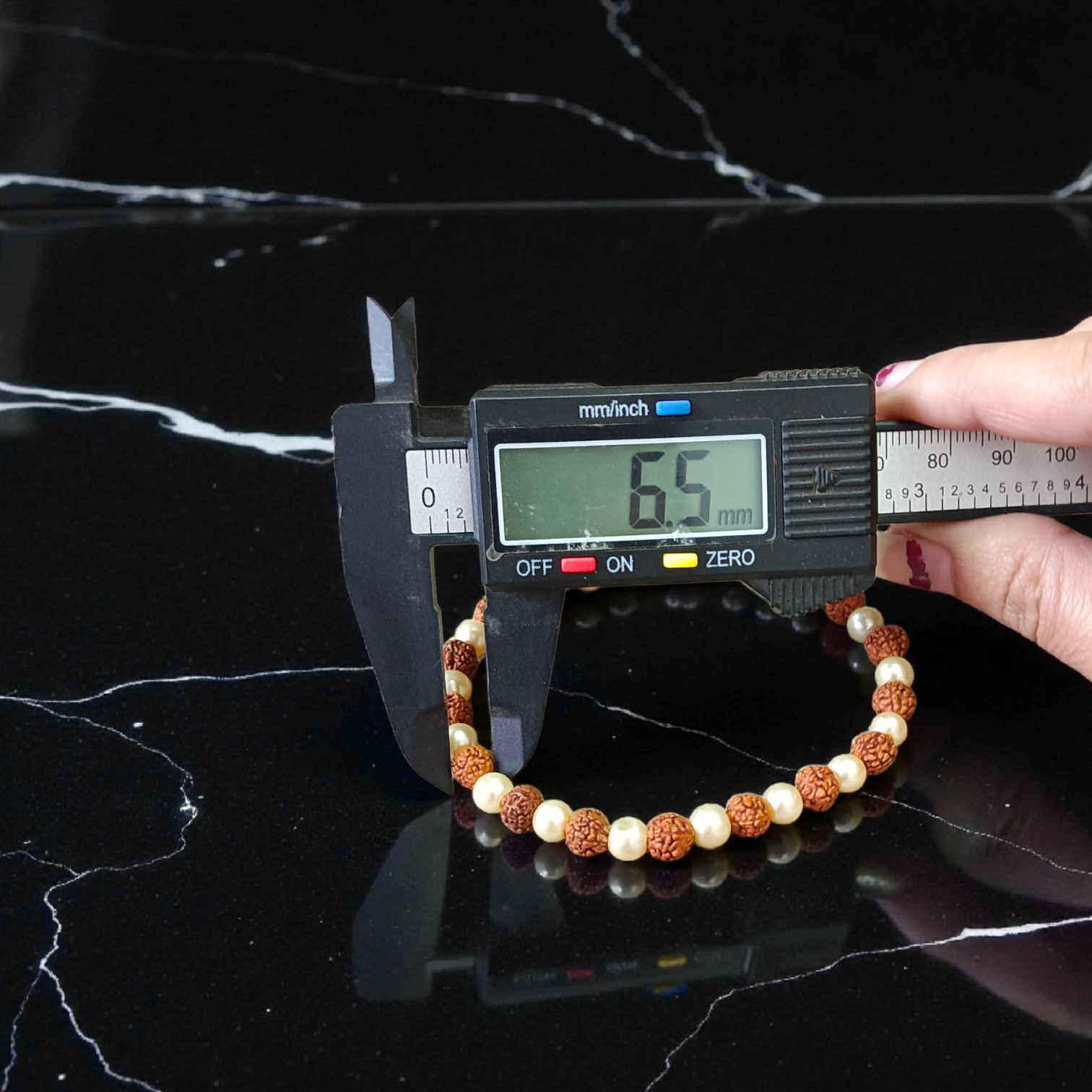 Rudraksha and Moti (Pearl) Bracelet with elegant design, stretchable, placed on a spiritual fabric background