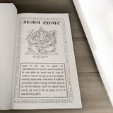 The Bhajan Sagar In Hindi book placed on a peaceful altar, with devotional symbols around it, symbolizing the power of music and prayer in spiritual practice