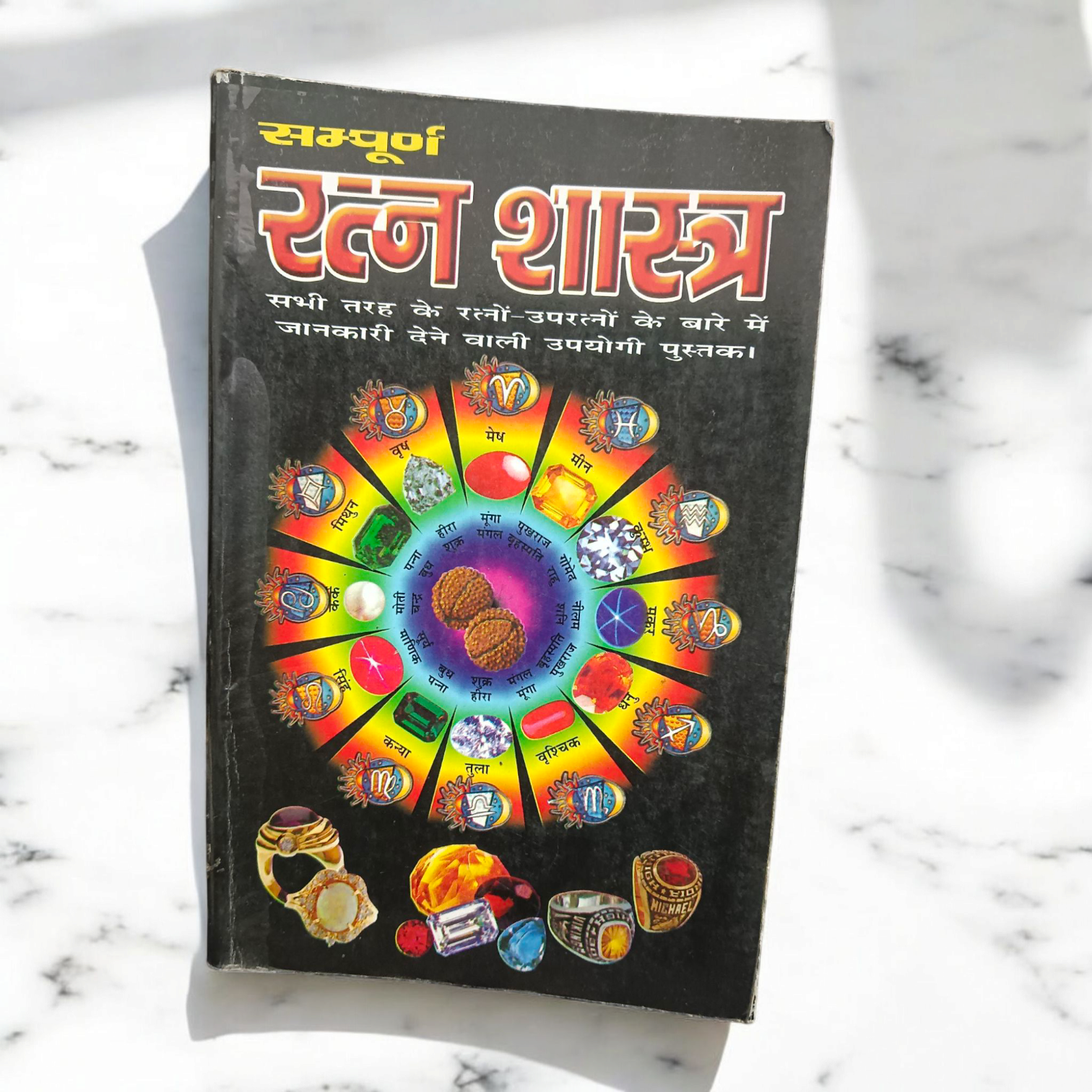The Ratan Shastra book displayed with various gemstones around it, symbolizing the spiritual and healing properties of gemstones in Vedic astrology.