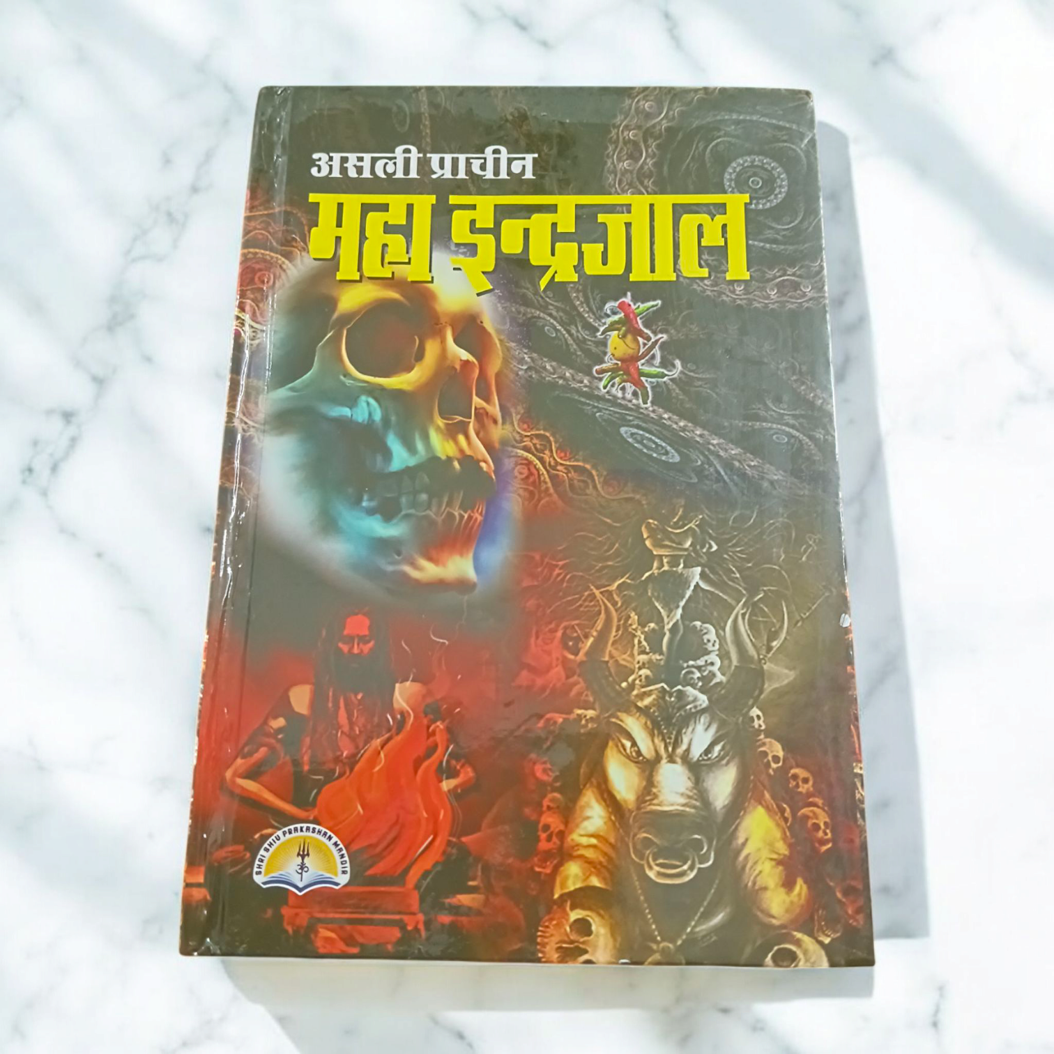 The book titled Asli Prachin Maha Indrajal on a dark mystical background, with symbols of red and black magic and protective rituals.