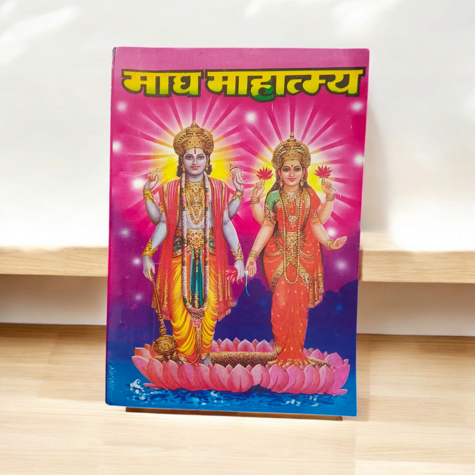 The image displays the cover of Magh Mahatmya | Hindi Book, featuring sacred symbols associated with the Magh month and the deities worshipped during this time.