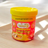 Three small containers of white, yellow, and red Chandan Tilak paste with a spiritual backdrop showcasing sandalwood and diya