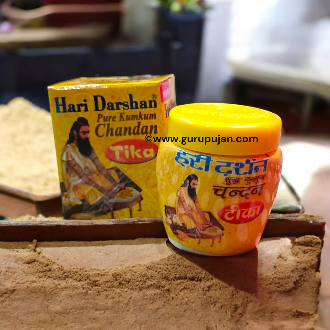 Three small containers of white, yellow, and red Chandan Tilak paste with a spiritual backdrop showcasing sandalwood and diya